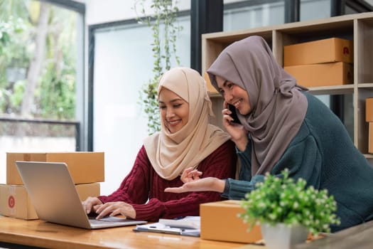 Muslim two woman freelancer sme business online shopping working on laptop computer and checklist order box at home Business online shipping and delivery concept.