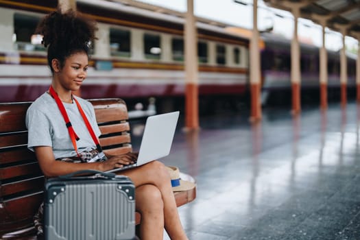 Asian teenage girl african american traveling using computer laptop while waiting for a train at a station