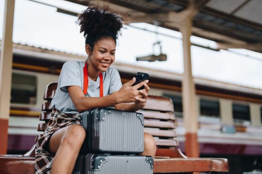 Asian teenage girl african american traveling using smartphone moblie while waiting for a train at a station