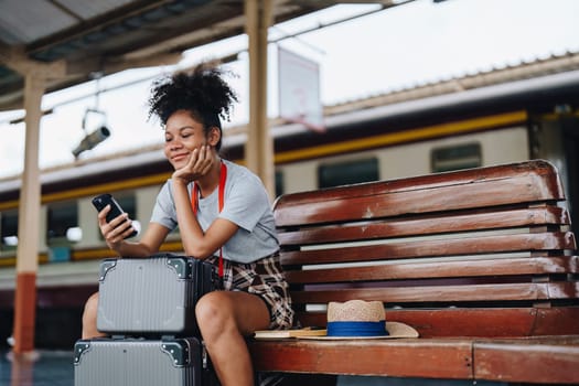 Asian teenage girl african american traveling using smartphone moblie while waiting for a train at a station