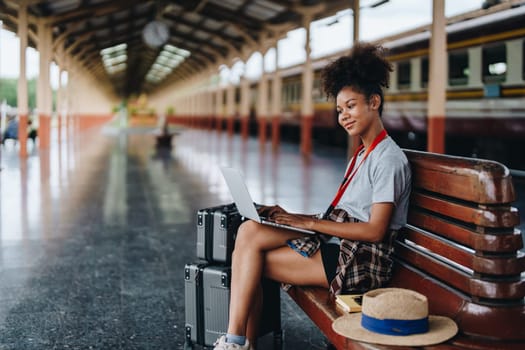 Asian teenage girl african american traveling using computer laptop while waiting for a train at a station