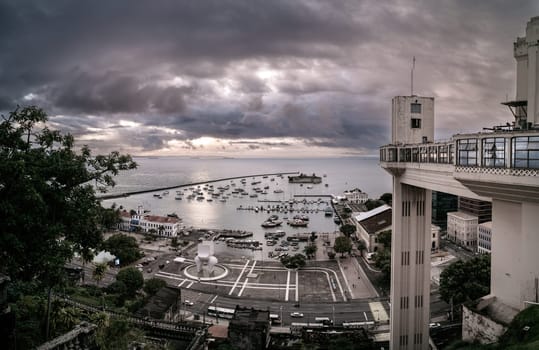 A vintage view of the Lacerda elevator in Salvador, Brazil, at dusk with clouds hovering over the sea during sunset. This is the world's first elevator.