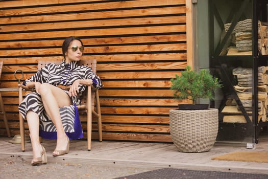 Beautiful girl relaxing on a resort. Woman in zebra dress sitting on chair.
