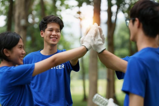 Young Asian Volunteers with garbage bags cleaning park area. Ecology, Charitable organization concept.