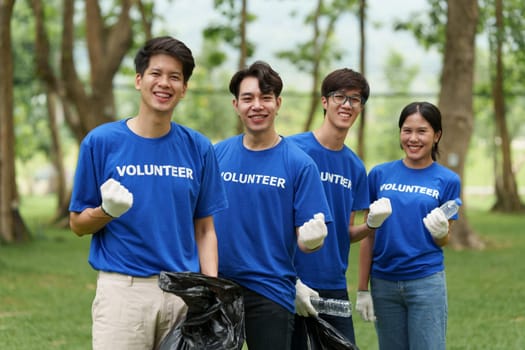 Young Asian Volunteers with garbage bags cleaning park area. Ecology, Charitable organization concept.