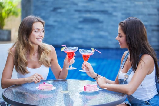 Two young women with cocktails outdoors at cafe