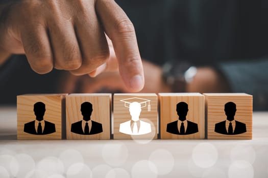 Hand points to a red human icon on a wooden block. Business hiring and recruitment selection in Human Resource Management. Leadership and teamwork for success in competitive market. Human resources