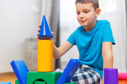 A child is playing with children building blocks on floor. Building a tower of cubes. Educational toys for children.