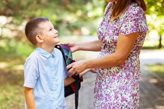 Back to school. Mother saying goodbye to her son as he leave for School. Schoolboy is ready go to school. First day at school.