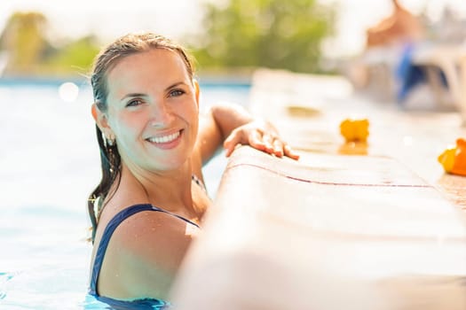 Portrait of relaxed, attractive tanned woman, lean on swimming pool edge, enjoying vacation. Sexy caucasian female relaxing in the pool at the resort.