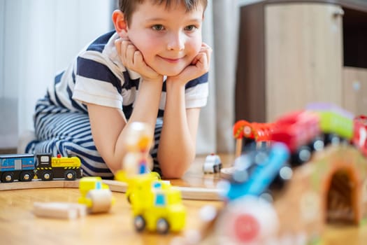 Cute boy is playing with toy railway road at home or in kindergarten on the floor. Child at home or in kindergarten.