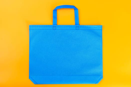 The blue shopping bag on a yellow background. Mockup for design. Shopping and sale concept.