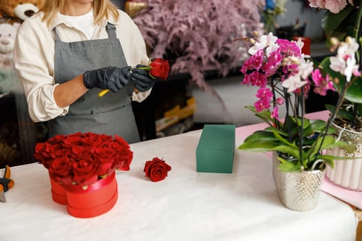 Female decorator creating beautiful composition at table. Lifestyle flower shop