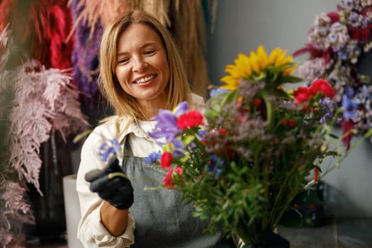 Female decorator creating beautiful bouquet at table. Lifestyle flower shop