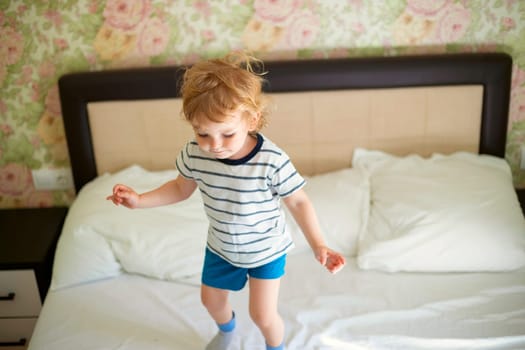 Just a woken up little child jumping on the bed. Happy child jumping and playing on the bed.