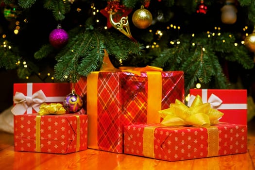 Pile of Christmas gift boxes on the floor under beautiful Christmas tree indoors