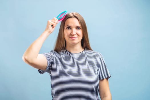 Young beautiful brunette woman brushing her long healthy hair. Haircare concept.