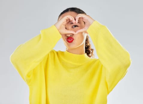 Woman, portrait and heart hands for love, care or romance in casual fashion against a white studio background. Female person with hand in support emoji, sign and symbol for health or wellness.