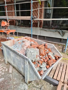 A container with rubble in front of a construction site