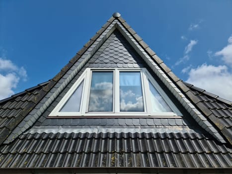 Open roof window in velux style with black roof tiles