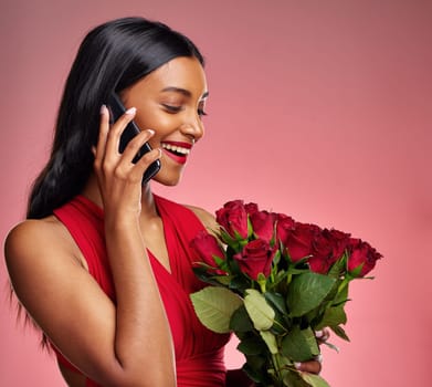 Phone call, talking and a woman with roses on a studio background for valentines day. Thank you, model and face of a young Indian girl with a flower bouquet and smartphone for romance or love on pink.