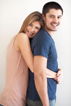 Portrait, hug and couple in studio happy, bonding and having fun against a wall background. Face, smile and woman embracing man with care, romance and love while enjoying their relationship together.