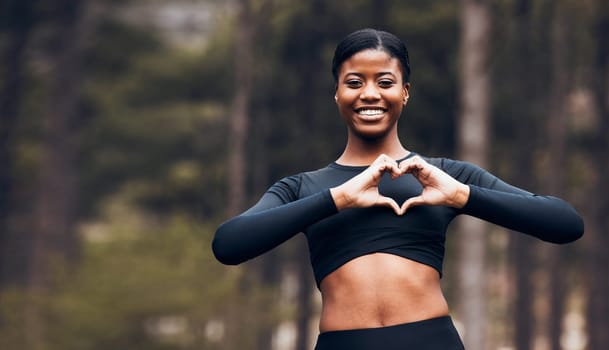 Heart hand, black woman and fitness in nature with exercise and fitness with love gesture. Sport, female person and support outdoor by the trees after a run with romance sign from a workout in park.