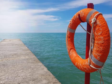 Lifebuoy on the background of the azure sea, sea pier in the sea, close-up, place for text.