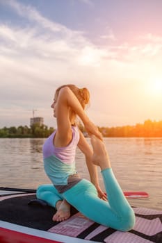 Young beautiful woman meditating in a sea at SUP paddleboarding. Healthy lifestyle. Girl in yoga pose relaxing in calm water.