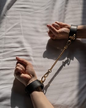 Close-up of woman's hands in leather handcuffs. Sex toy