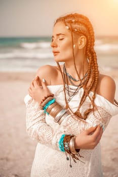 Woman portret sea white dress. Model in boho style in a white long dress and silver jewelry on the beach. Her hair is braided, and there are many bracelets on her arms