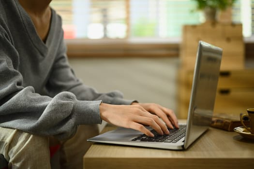 Cropped shot of young woman hands typing on laptop, communicating online, working remote from home.