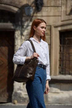 photo of a woman with a leather bag. the girl is dressed in jeans and white blouse