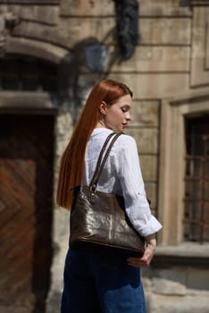 photo of a woman with a leather bag. the girl is dressed in jeans and white blouse