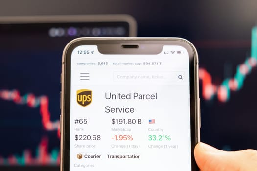 United Parcel Service stock price on the screen of cell phone in mans hand with changing stock market exchange with trading candlestick graph analysis, February 2022, San Francisco, USA