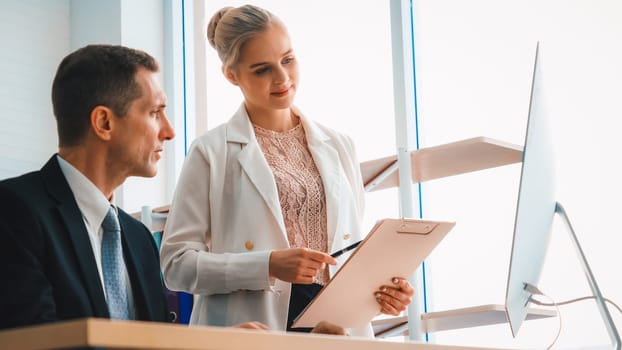 Two business people talk project strategy at office meeting room. Businessman discuss project planning with colleague at modern workplace while having conversation and advice on financial report. Jivy