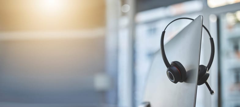 Call center, headset on a computer in an empty office with flare and mockup for communication or assistance. Customer care, support and equipment in a workplace after hours for help or service.