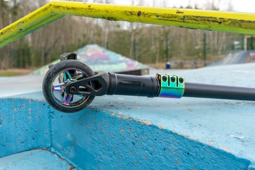 a stunt scooter, a modern extreme stunt scooter in a skate park lies on a concrete path. the scratched scooter lies after falling to the ground. The concept of a healthy lifestyle and sports leisure