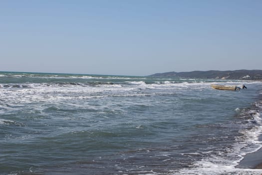 Boat near the sea shore at daytime. Boat used for fishing. Sea waves