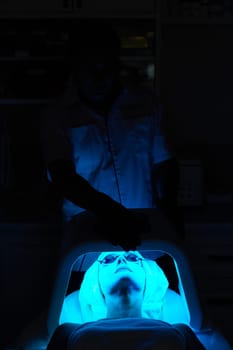 Woman in protective glasses getting facial treatment with led therapy. LED mask at the beauty clinic