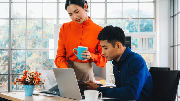 Two business people talk project strategy at office meeting room. Businessman discuss project planning with colleague at modern workplace while having conversation and advice on financial report. Jivy