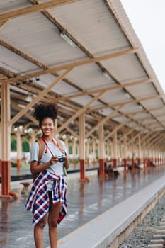 Asian teenage girl african american traveling using a camera take a photo to capture memories while waiting for a train at the station