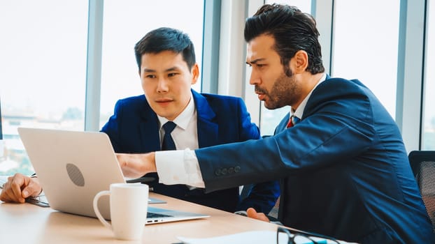 Two business people talk project strategy at office meeting room. Businessman discuss project planning with colleague at modern workplace while having conversation and advice on financial report. Jivy