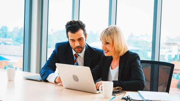 Two business people talk project strategy at office meeting room. Businessman discuss project planning with colleague at modern workplace while having conversation and advice on financial report. Jivy