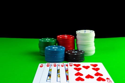Poker chips in stacks and royal flush cards on the poker table. Cards on the table with a combination of royal flush and poker chips.