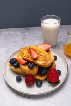 Torrijas, Spanish Style French Toast Served With Orange Topping, Glaze, Fresh Blueberries, Strawberry On Green Plate, Wooden Table. A Half Of Orange. Spanish Dessert. Horizontal plane.