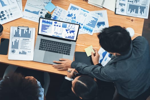 Multiracial analyst team use BI Fintech software to analyze financial data on meeting. Top view finance dashboard data display on laptop screen with analyzed chart for marketing indication. Concord