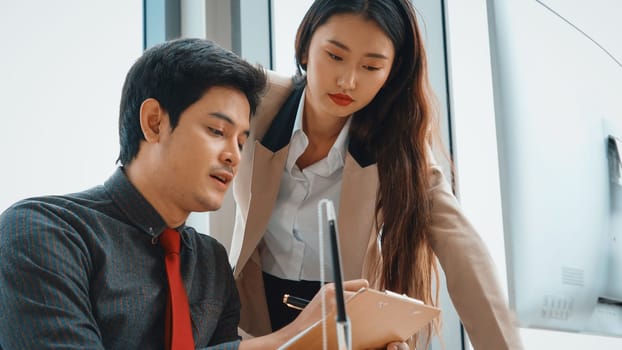 Two business people talk project strategy at office meeting room. Businessman discuss project planning with colleague at modern workplace while having conversation and advice on financial report. Jivy