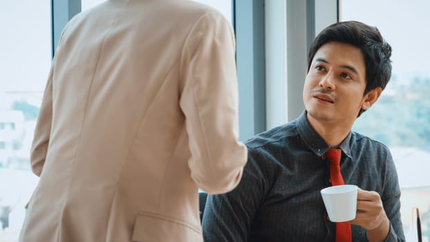 Two business people talk project strategy at office meeting room. Businessman discuss project planning with colleague at modern workplace while having conversation and advice on financial report. Jivy