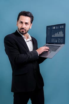 Successful businessman in black suit with innovative tech concept, standing pose and holding laptop and smiling with excitement on copyspace background for promotion or advertisement. Fervent